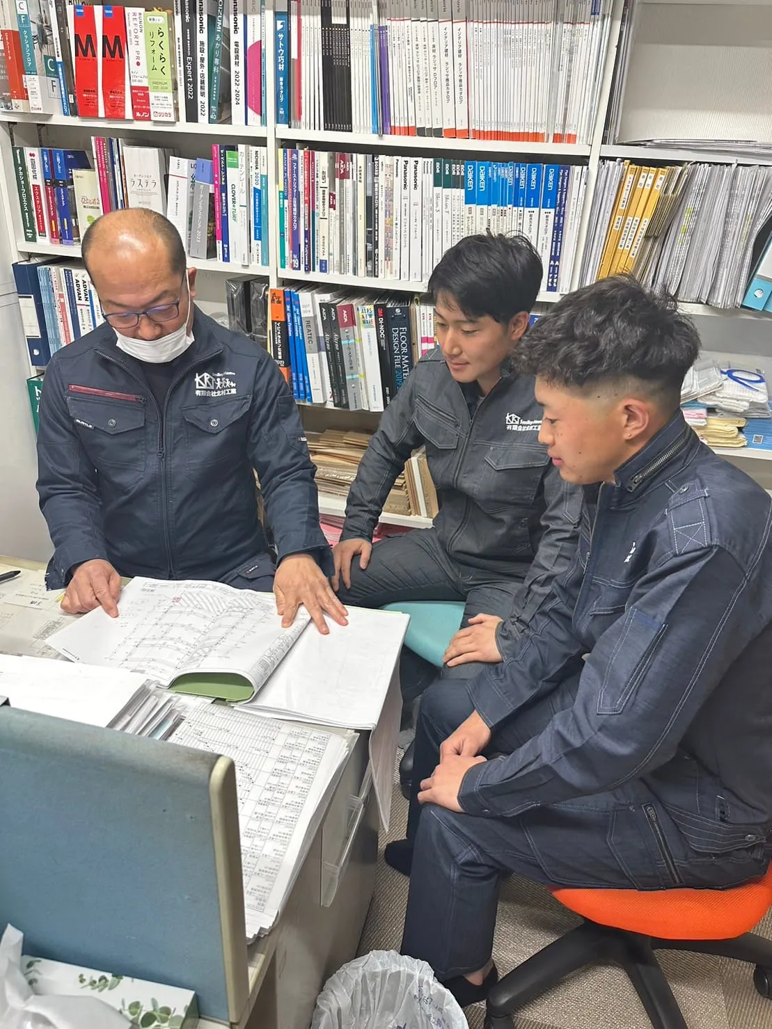 図面を見ながら先輩社員が若手に教えている様子